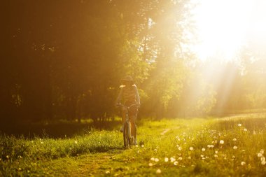Komik kız sürüş Bisiklet açık. Güneşli yaz yaşam tarzı kavramı. Kadın elbise ve şapka alanında dandelions. Kadın araba park. Metin ışık fotoğraf efekti. Boşaltmak için tasarım.