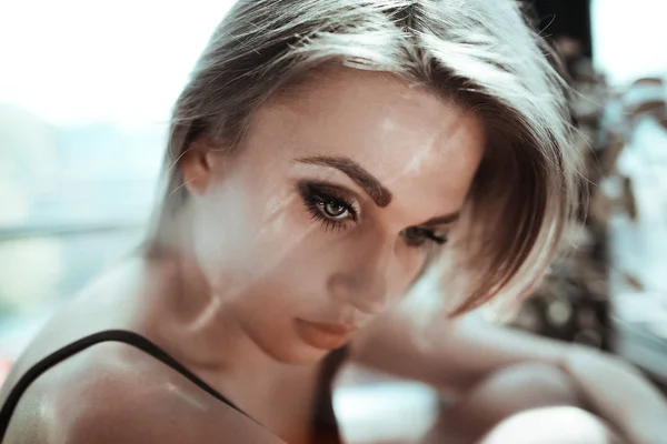 Närbild porträtt av en vacker ung kvinna med blont hår. Flare ljus fotoeffekt. Flicka med naken make up, mode ögonbryn och gröna ögon. Skönhet-konceptet — Stockfoto