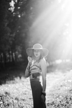 Kız Açık parkta yürüyüş silüeti. Güneşli yaz yaşam tarzı kavramı. Kadın elbise ve şapka dandelions alanı. Metin ışık efekti. Boşaltmak için tasarım. BW fotoğraf.