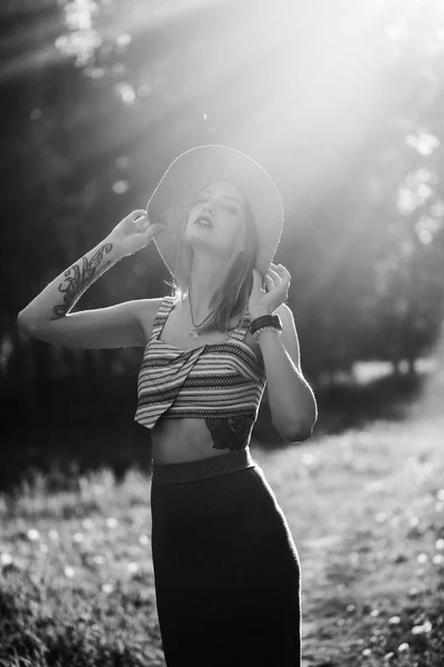 Silhueta de menina que anda no parque ao ar livre. Conceito de estilo de vida ensolarado verão. Mulher de vestido e chapéu no campo com dentes-de-leão. Efeito de luz para texto. Copyspace para design. Foto BW . — Fotografia de Stock