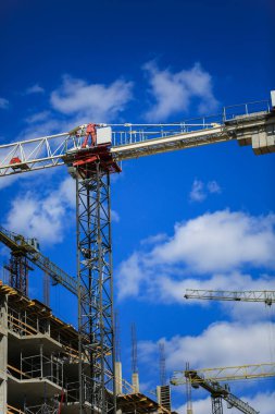 İnşaat kavramı. Gökyüzü inşaat altında yeni bir yapı. Mavi arka plan. Yeni Kentsel şehir. Makine, vinçler ve İskele inşaatçılar. Ağır sanayi ve iş güvenliği