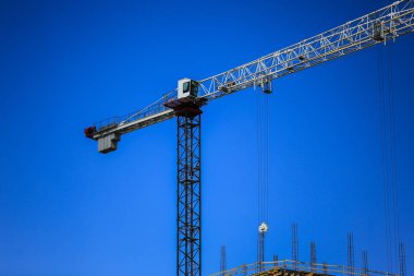 İnşaat kavramı. Gökyüzü inşaat altında yeni bir yapı. Mavi arka plan. Yeni Kentsel şehir. Makine, vinçler ve İskele inşaatçılar. Ağır sanayi ve iş güvenliği
