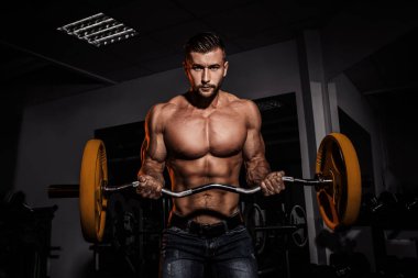adam içinde jimnastik salonu. Halter alıştırmalar yapan kaslı vücut geliştirmeci adam. Güçlü kişi. Spor arka plan. Genç atlet ağırlık kaldırma için eğitim hazır