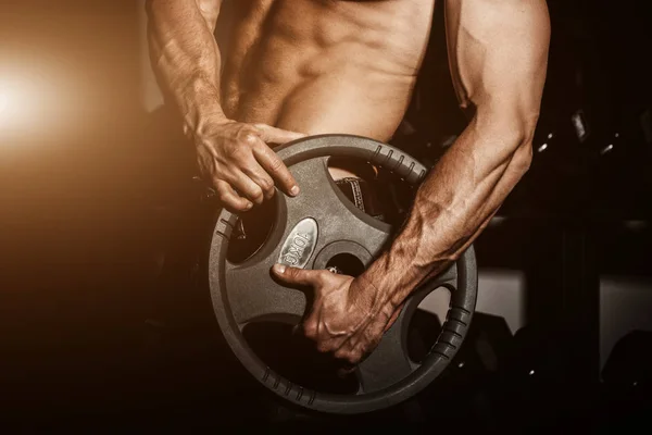 Man in gym. Muscular bodybuilder guy doing exercises with barbell. Strong person with Tense strong male hand with veins barbell.Flare for text and design. — Stock Photo, Image