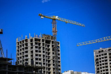 İnşaat kavramı. Gökyüzü inşaat altında yeni bir yapı. Mavi arka plan. Yeni Kentsel şehir. Makine, vinçler ve İskele inşaatçılar. Ağır sanayi ve iş güvenliği