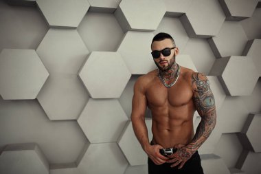 Seksi closeup moda dövme ve ayakta ve testler için veya günlüğe trend moda giysiler içinde poz siyah sakalı ile şık yakışıklı bir erkek model üstsüz portresi. Profesyonel Studio resim.