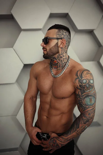 Sexy primer plano topless retrato de elegante modelo masculino guapo con tatuaje de moda y una barba negra de pie y posando para las pruebas o para diario en la moda ropa de moda. Imagen de estudio profesional . — Foto de Stock