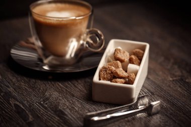 bir fincan kahve kahve dükkanı vintage renkli. Kahve Öğütücü ve kahverengi şeker kamışı parlama ile ahşap masa üzerinde arka plan bulanık. Retro tarzı