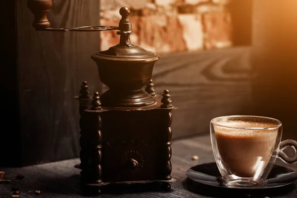 Filiżanka kawy w kawiarni vintage kolor. Młynki do kawy i brązowy cukier trzcinowy na drewnianym stole z pochodni niewyraźne tło. Styl retro — Zdjęcie stockowe