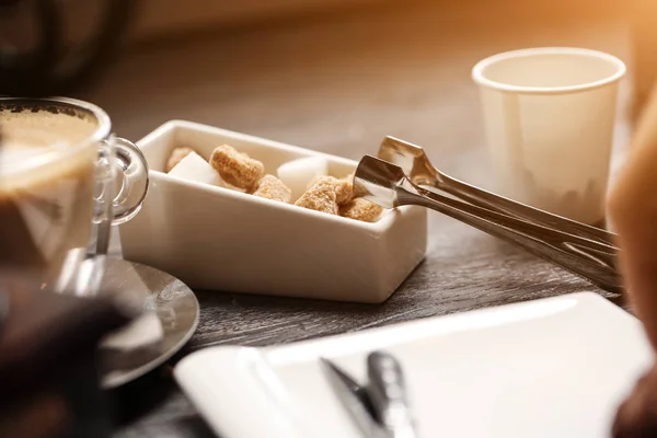 Taza de café en la cafetería de color vintage. Molinillo de café y azúcar de caña marrón en la mesa de madera con fondo borroso llamarada. Estilo retro — Foto de Stock