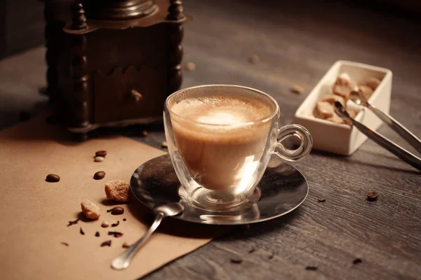 Taza de café en la cafetería de color vintage. Molinillo de café y azúcar de caña marrón en la mesa de madera con fondo borroso llamarada. Estilo retro — Foto de Stock