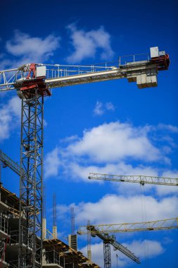 İnşaat kavramı. Gökyüzü inşaat altında yeni bir yapı. Mavi arka plan. Yeni Kentsel şehir. Makine, vinçler ve İskele inşaatçılar. Ağır sanayi ve iş güvenliği