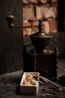 bir fincan kahve kahve dükkanı vintage renkli. Kahve Öğütücü ve kahverengi şeker kamışı parlama ile ahşap masa üzerinde arka plan bulanık. Retro tarzı