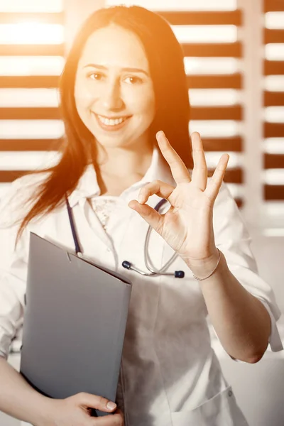 Joven feliz médico alegre en uniforme blanco gesto ok — Foto de Stock