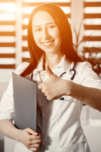 Joven feliz médico alegre en uniforme blanco mostrando OK o signo de aprobación con el pulgar hacia arriba — Foto de Stock