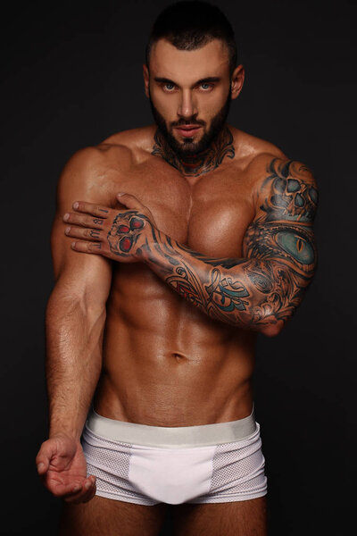 Сексуальный крупным планом портрет красивой топлесс мужской модели с красивыми глазами. Сексуальный мужчина или мускулистый мачо, бодибилдер, с мышечным туловищем, тело с шестью пачками и прессом позирует на черном фоне в белом
