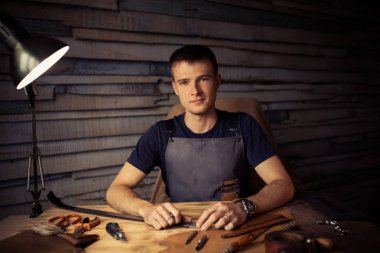 Deri kemer deri atölyesinde çalışma süreci. Adam holding işçiliği aracı ve çalışma. Tanner eski Tabakhane içinde. Ahşap masa arka plan. Adam kolunu kapatın