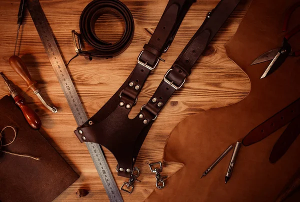 Lederhandwerk und Gürtel für Fotografen. Gerber-Werkzeuge auf grauem Holzhintergrund von oben — Stockfoto