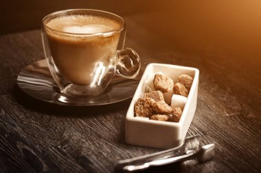 bir fincan kahve kahve dükkanı vintage renkli. Kahve Öğütücü ve kahverengi şeker kamışı parlama ile ahşap masa üzerinde arka plan bulanık. Retro tarzı görüntü. Parlama ışık