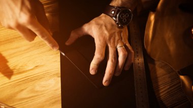 Deri kemer deri atölyesinde çalışma süreci. Adam holding aracı. Tanner eski Tabakhane içinde. Ahşap masa arka plan. Adam kolunu kapatın. Sıcak ışık metin ve tasarım için. Web afiş boyutu