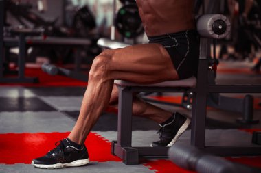 Sporcu spor salonunda. Çalışmaları yapan adam. Bacaklar damarlar ile portre portre. Erkek model tabaklanmış deri ile. Seksi erkek vücut geliştirmeci barbell ile ayakta.