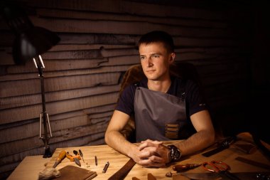 Deri kemer deri atölyesinde çalışma süreci. Holding adam ahşap masa üzerinde eller. Araçlar arka plan üzerinde işçiliği. Tanner eski Tabakhane içinde. Erkekler kol kapatın. Parmakları birleştirin