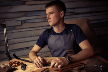 Deri kemer deri atölyesinde çalışma süreci. Adam holding işçiliği aracı ve çalışma. Tanner eski Tabakhane içinde. Ahşap masa arka plan. Adam kolunu kapatın