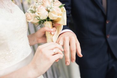 Kadının elinde büyük güzel düğün buketi. Gelin Damat parmağında yüzük koyar