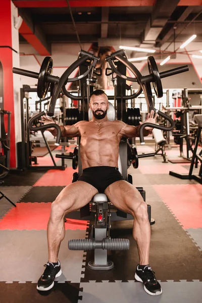 Man in sport theme. Sportsman working out in gym. Muscular bodybuilder doing exercises