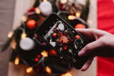 Kadının elini yeni yıl çelenk ile Gingerbread çerezleri Noel partisi için bir hareket eden fotoğraf al. Pasta grup odak üstünde. Noel arifesi tasarım