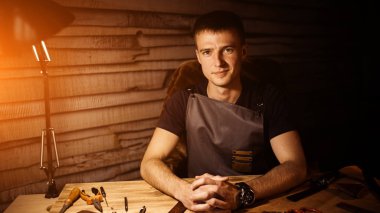 Deri kemer deri atölyesinde çalışma süreci. Holding adam ahşap masa üzerinde eller. Araçlar arka plan üzerinde işçiliği. Tanner eski Tabakhane içinde. Sıcak ışık metin ve tasarım için. Web afiş boyutu