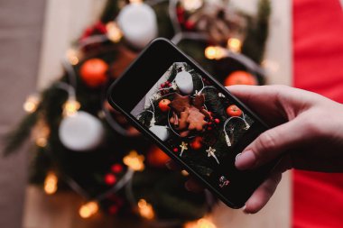 Kadının elini yeni yıl çelenk ile Gingerbread çerezleri Noel partisi için bir hareket eden fotoğraf al. Pasta grup odak üstünde. Noel arifesi tasarım