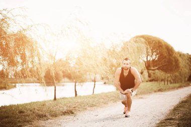 Akşam güneş ışığında çalışan. Aktif spor kavram. Sağlıklı sporcu sokakta egzersizleri yapıyor. Runner Park fitness izci ile. Yorgun atlet spor giyim almak bir duraklama
