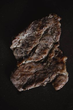 Gıda Fotoğraf rustik tarzda. Izgara et. Koyu siyah arka plan kayrak plaka üzerinde domuz biftek. Üstten Görünüm. Düz yatıyordu
