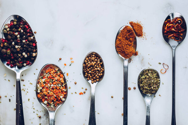 Spices in spoons top view. Closeup macro photo. Stone marble table background. Flat lay in rustic vintage color toning