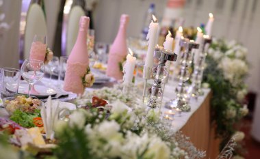 Metal sarısı avize üzerine beyaz mumlar restorandaki lüks düğün resepsiyonunda masaların üzerinde duruyor. şık dekorasyon ve süslemeler.