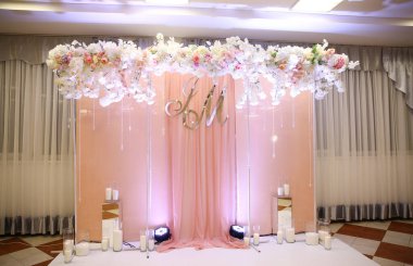 Düğün salonunda ışıklandırma ve çiçeklerle dekoratif fotoğraf bölgesi.