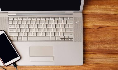 Tahta masadaki dizüstü bilgisayar ve cep telefonunun üst görüntüsü
