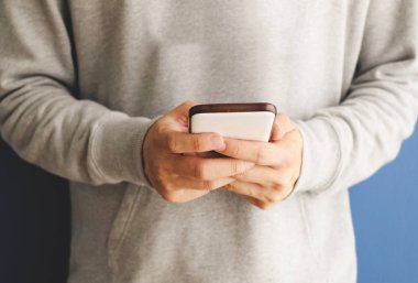 Mavi arka planda cep telefonu tutan bir adam