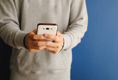 Mavi arka planda cep telefonu tutan bir adam