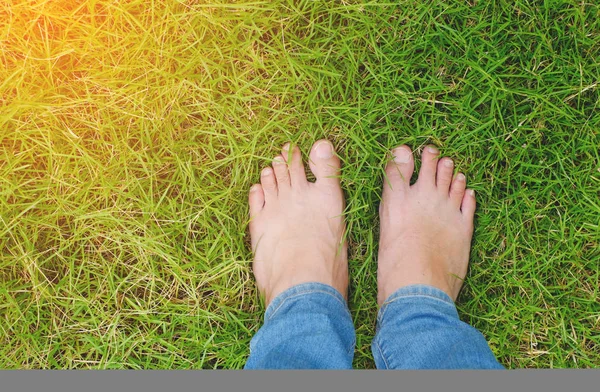 Yeşil çimlerin üzerinde yalınayak turuncu ışıkla