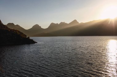 Güneş ışınları dağların üzerinden geçer ve göl suyuna ve karaya vurur. İspanya 'nın kuzeyinin kırsal kesiminde manzara. Yürüyüşçüler için ideal. İnanılmaz gün batımı
