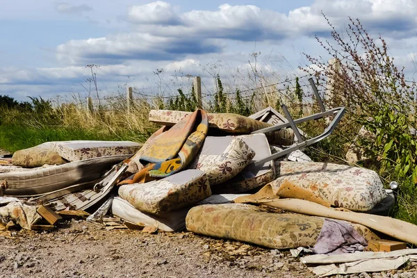 Kullanılmış köy yolunda bırakılmış bir yığın yasa dışı çöplük. Çevresel tehlike, mobilyalarla birlikte. Döşekler ve halılar. Sinek uçlu döküntü. Oxfordshire.