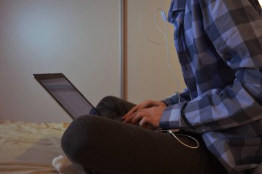 Evde dizüstü bilgisayarı olan genç bir adam.