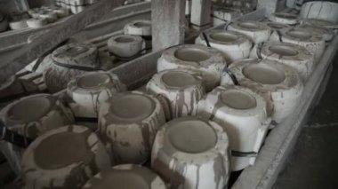 Atölye. Ahşap raflardaki çömlekçilik formları. Yavaş panorama ileri. Gri tonlu. Kapat..