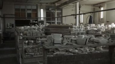 Clay atölyesi. Ahşap raflar. Tabak yapmak için kil dökme biçimleri. Genel plan. Devam edelim. Gri Tonlama.