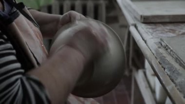 Clay atölyesi. Islak bir bezi tutan kadınsı ellerle dolu. Kil tenceresindeki pürüzü kaldır. Kapatın. Gri Tonlama.