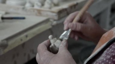 Clay atölyesi. Kadınların elleri ıslak bir sünger ve küçük bir çaydanlık üzerindeki pürüzle korunur. Kapatın. Gri Tonlama.