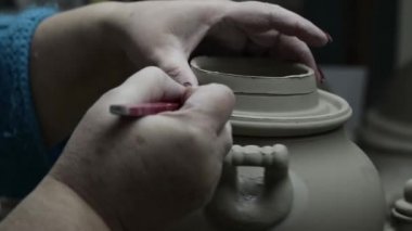 Atölye. Kadının elleri semaver kapağının kenarlarını bir yığın ile kesmiş, kapağı ters çevirmiş, pürüzü gidermiş ve sapları için çentik oluşturmuş. Gri tonlu. Kapat..