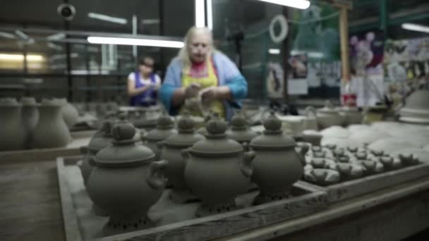 ピッチャー サモヴァールはミニケトルの上にあります 背景には二人の女性が次々と座り 陶器を扱う パノラマ右から左へ簡単に迂回 — ストック動画